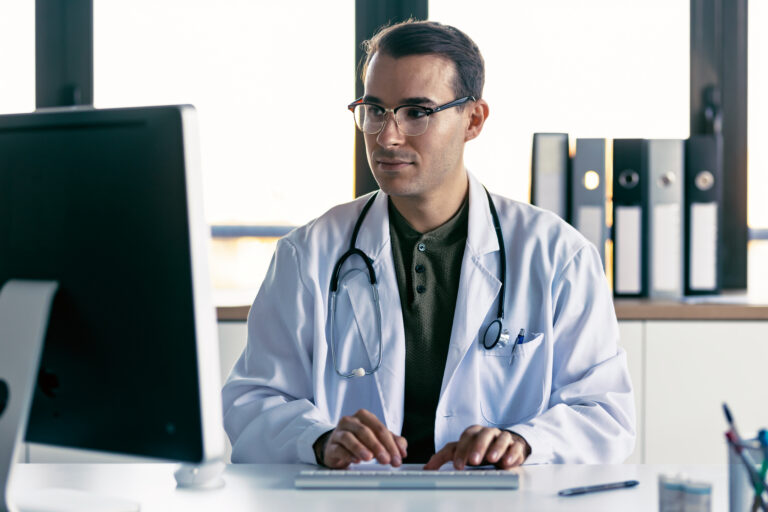 Shot of smart male doctor working with computer in the medical consultation