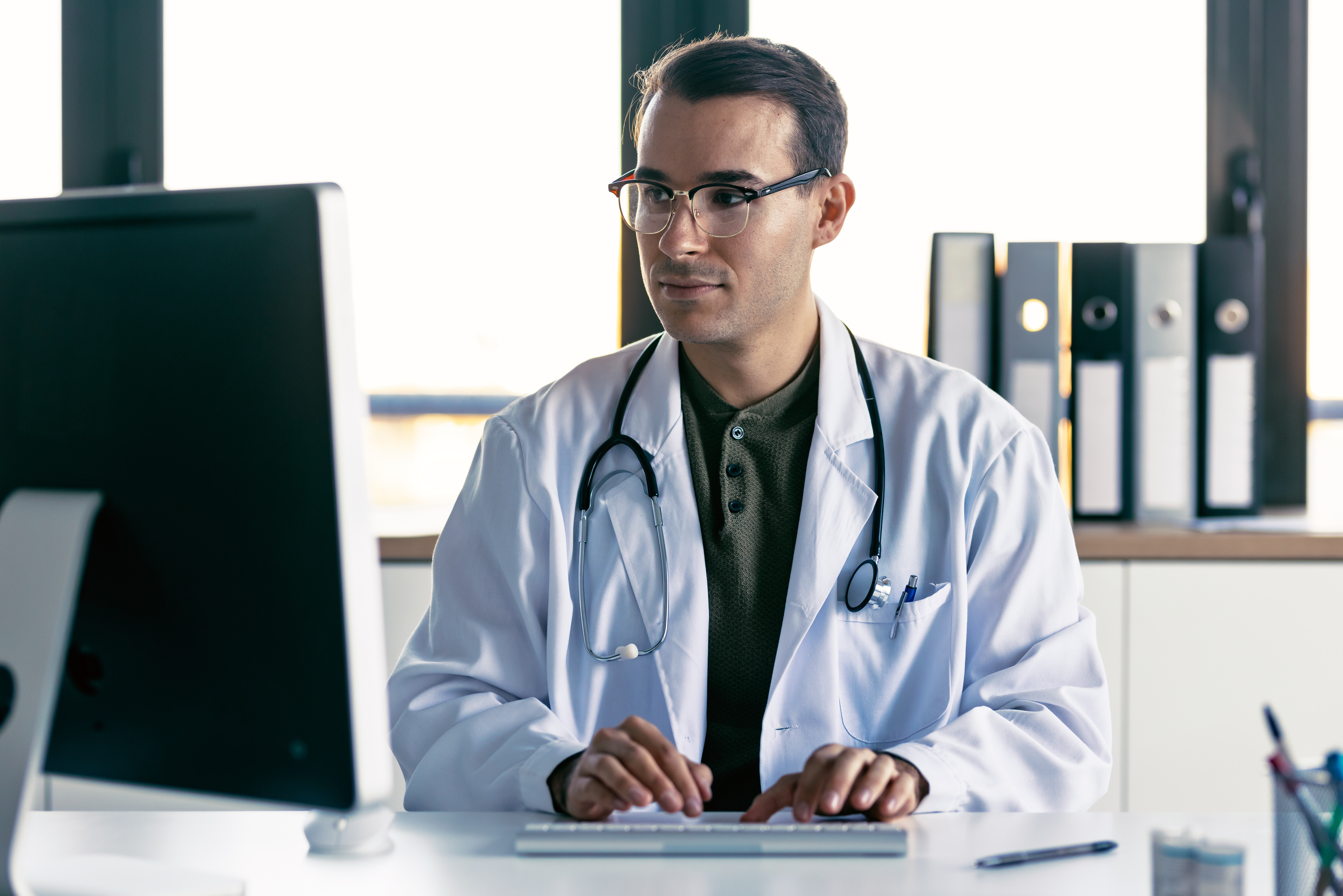Shot of smart male doctor working with computer in the medical consultation