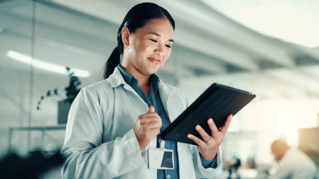 Scientist, woman and happy with tablet at lab for progress report, review and scroll for medical research. Person, smile and digital touchscreen with application for results for pharmaceutical study.