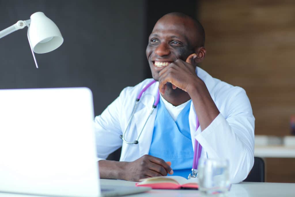 Young african doctor working on laptop at desk. Doctor. Workplace.