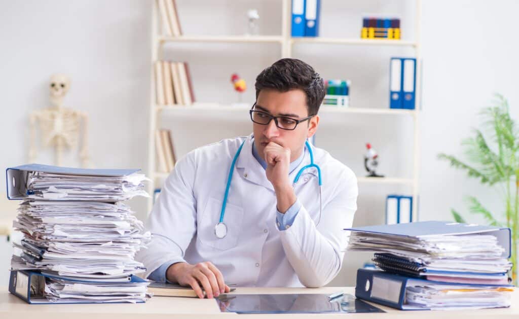Physician comparing paper records with digital EHRs