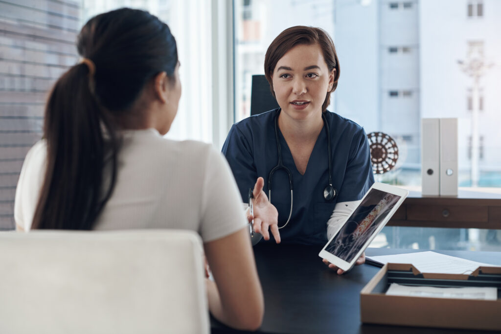 Shot of a young female doctor showing a patient a digital x-ray in an office.
