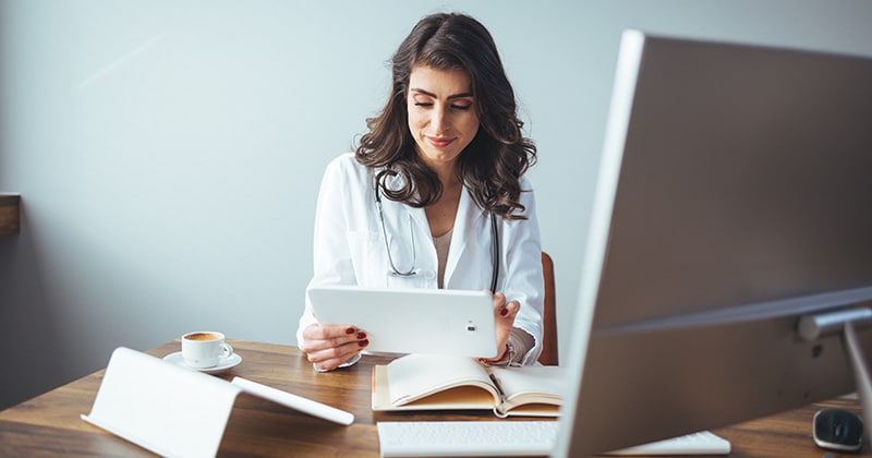 Healthcare professional analyzing data on a digital tablet.